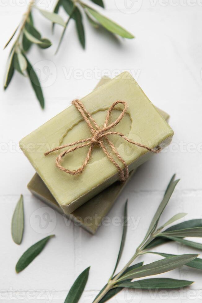 Natural soap bars tied with twine on white tile background photo