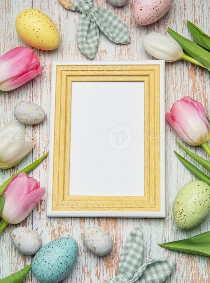 Easter eggs and tulips framing blank picture frame on wooden photo