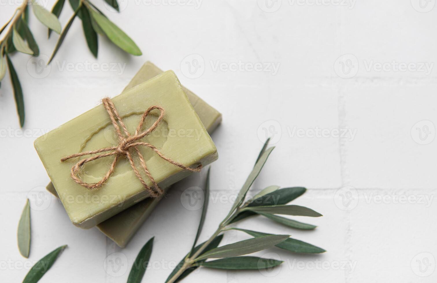 Natural olive soap bars tied with twine on white tile background photo