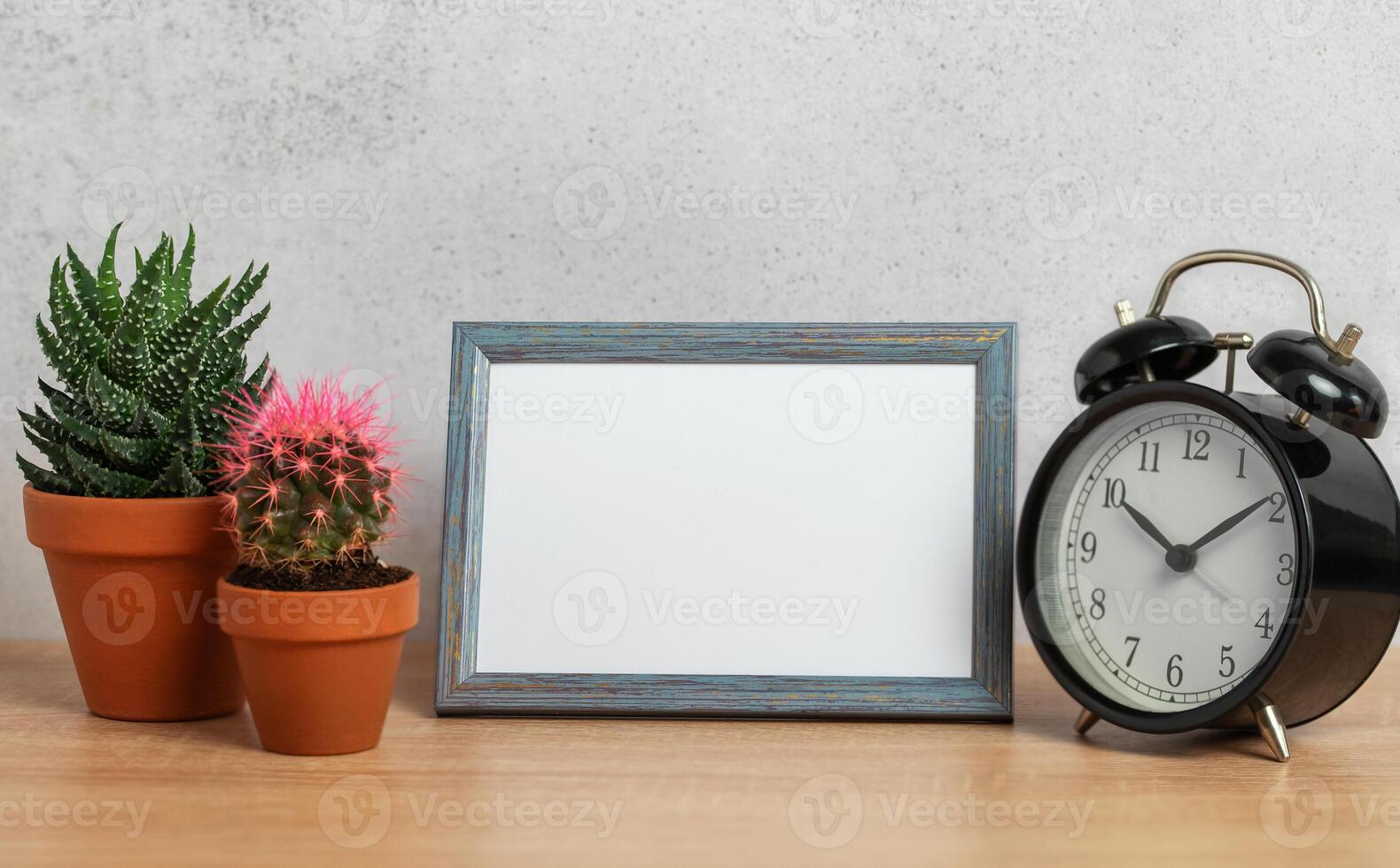 Empty frame, alarm clock and potted plants creating cozy home atmosphere photo
