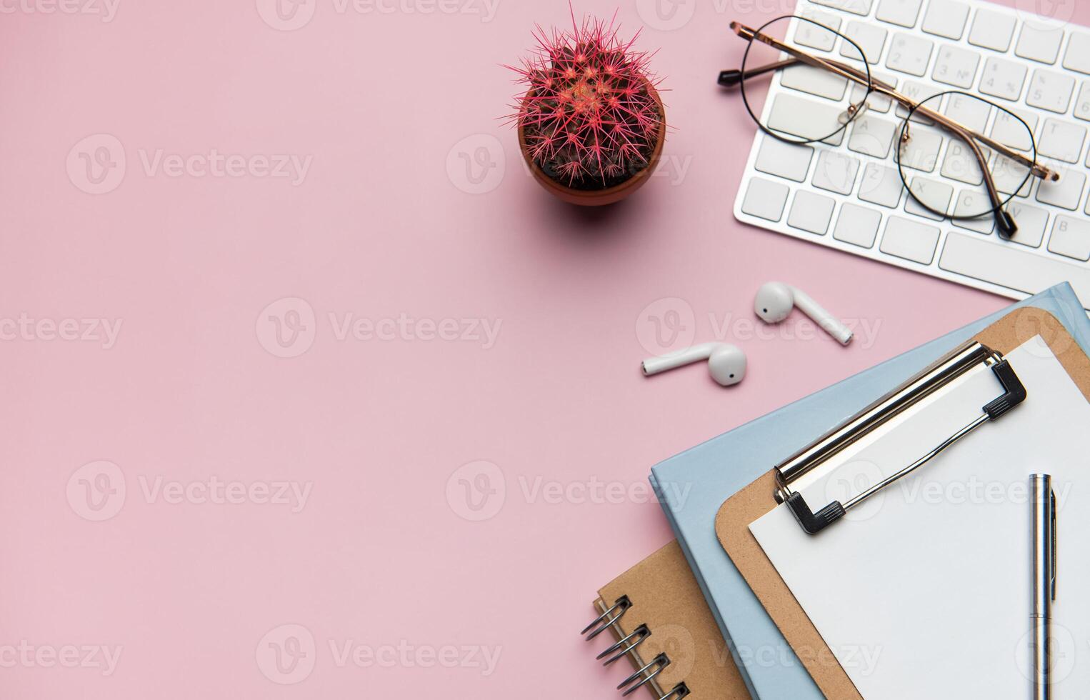 Workspace accessories on pink table with plant and keyboard photo