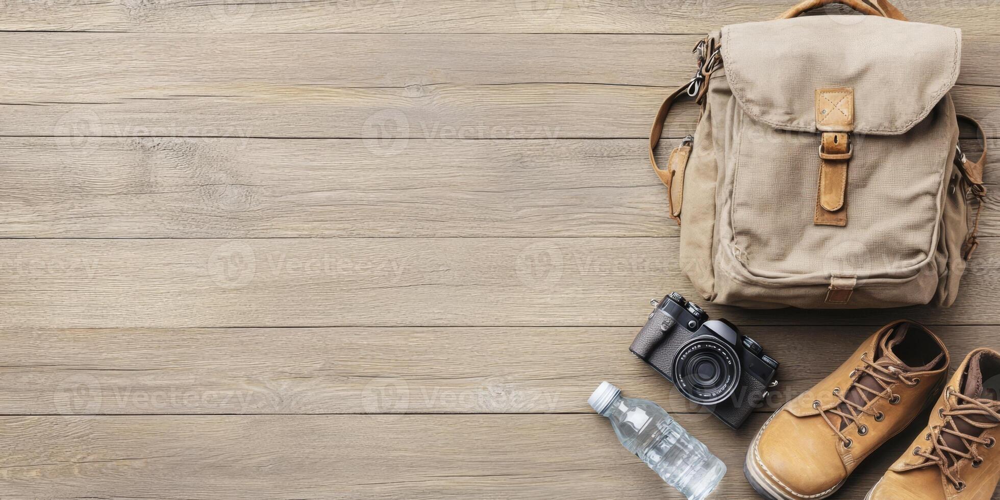 Travel backpack, hiking boots, water bottle, and camera await outdoor adventures on a wooden floor photo