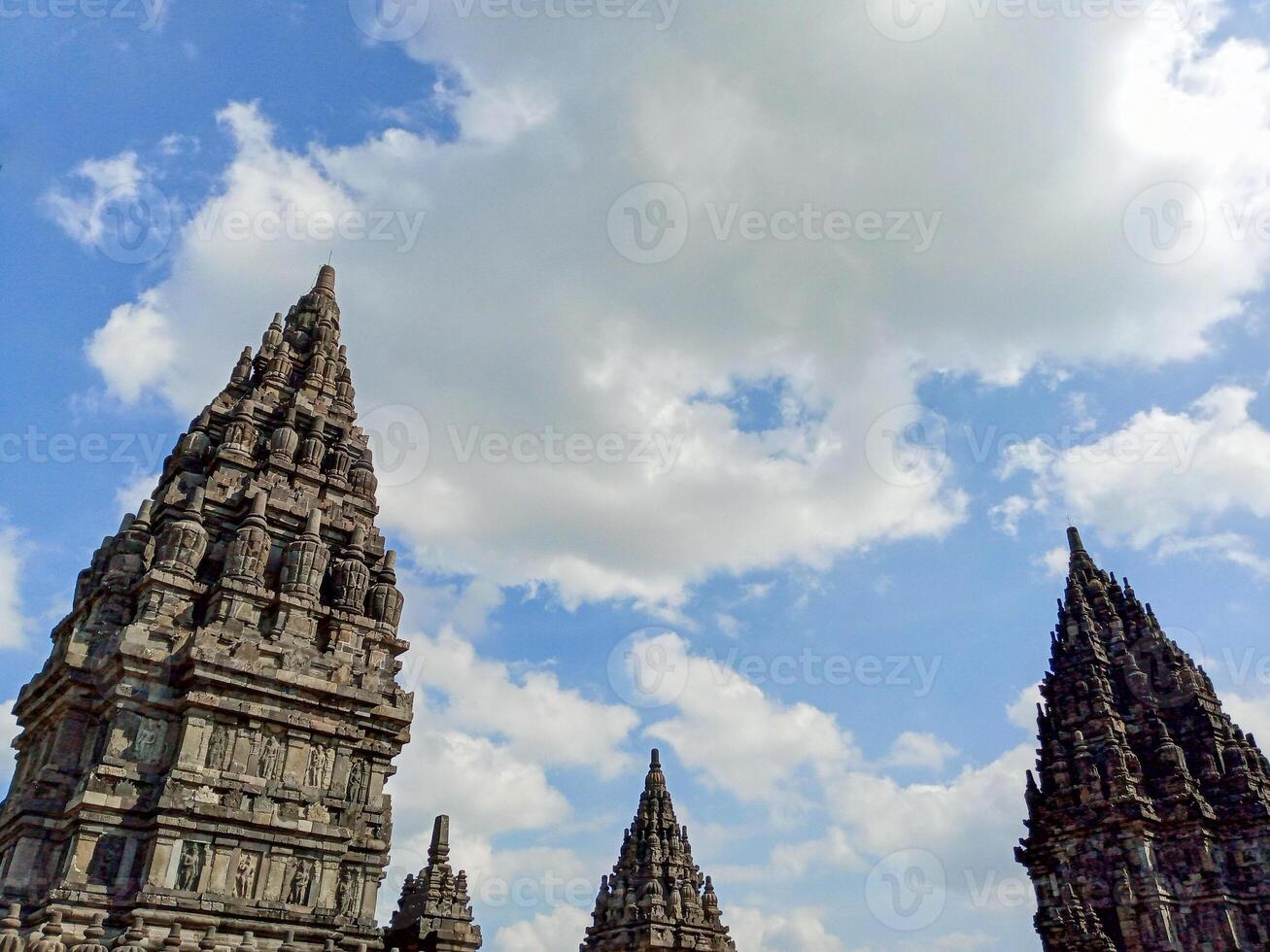 Prambanan Temple spires against a blue sky with white clouds. photo