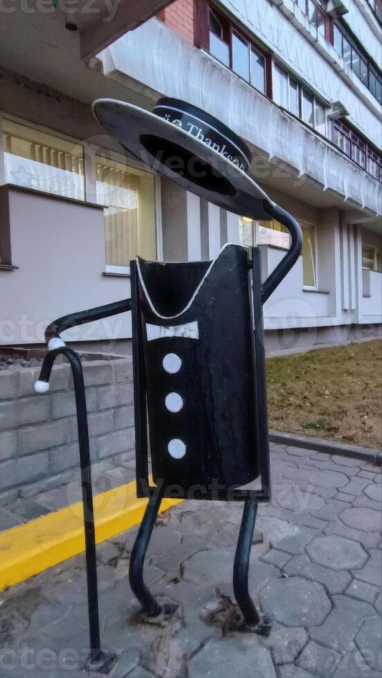 A creatively designed trash can resembling a figure in a tuxedo, showcasing artistic public furniture that encourages waste disposal in a fun way. photo