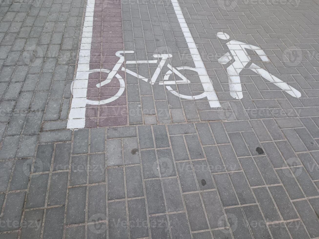 A bicycle lane and pedestrian symbol painted on the pavement, indicating designated paths for cyclists and walkers in an urban setting. photo