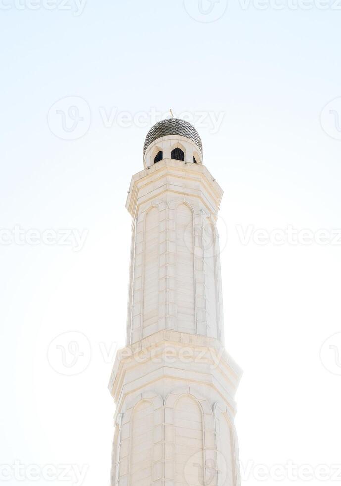 A serene white mosque minaret against a bright sky photo