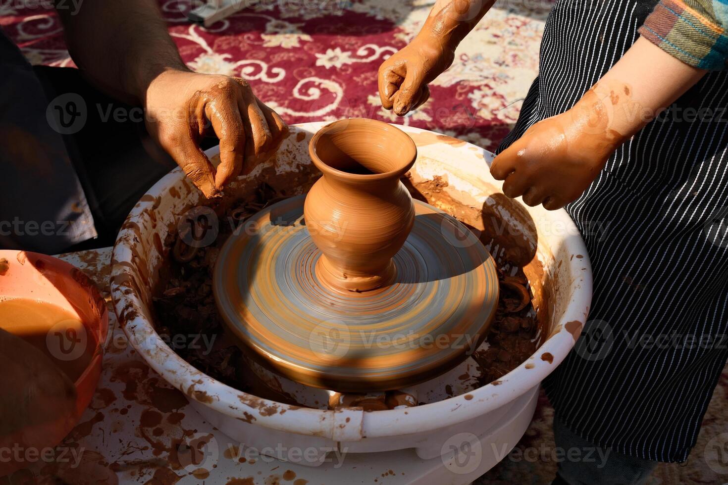 Making clay pottery by a master together with a kid photo