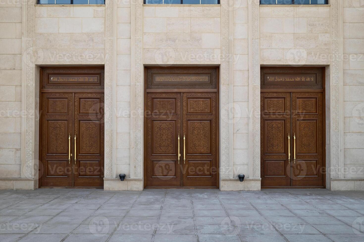 wooden doors with golden handles in front of a stone building photo