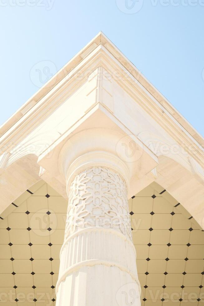 Architectural column and geometric ceiling under a clear blue sky photo