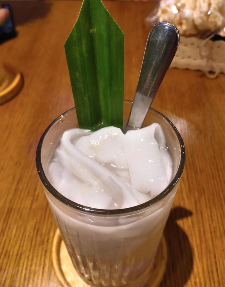 Pandan Coconut Ice with pandan leaf piece and a stainless steel spoon on table photo