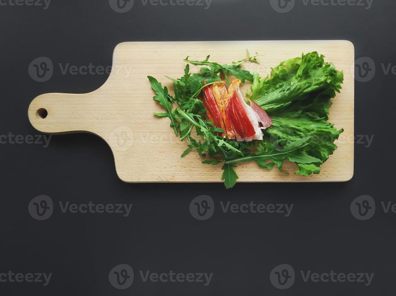 Sliced ham with a green lettuce leaves on a cutting board. photo