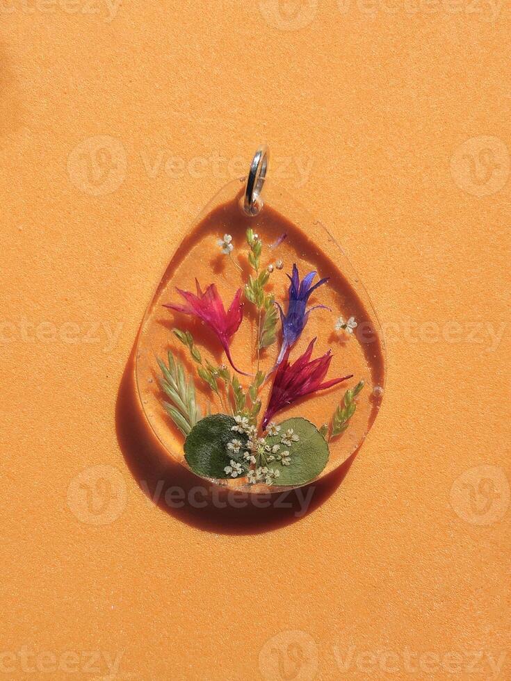 An epoxy resin pendant with dried flowers. photo