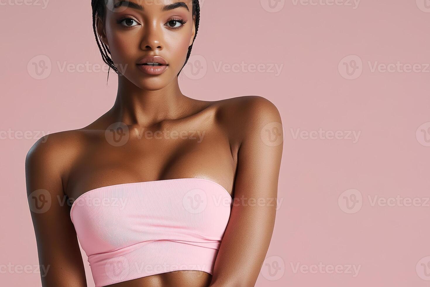 Charming African woman poses confidently in elegant pastel-pink athleisure wear showcasing her sculpted figure and radiant beauty photo