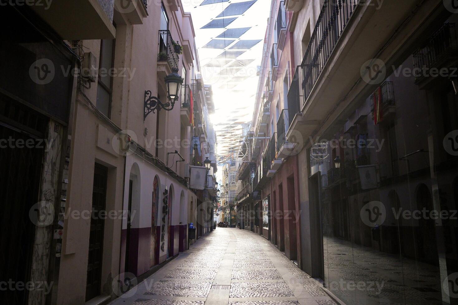 Narrow pedestrian street with sunshades and balconies in Badajoz historic center photo