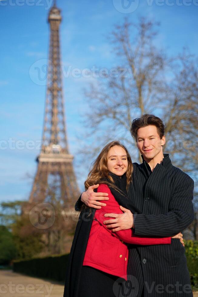 Romantic couple embraces lovingly near the Eiffel Tower in Paris, capturing a heartfelt moment in a classic travel destination. photo