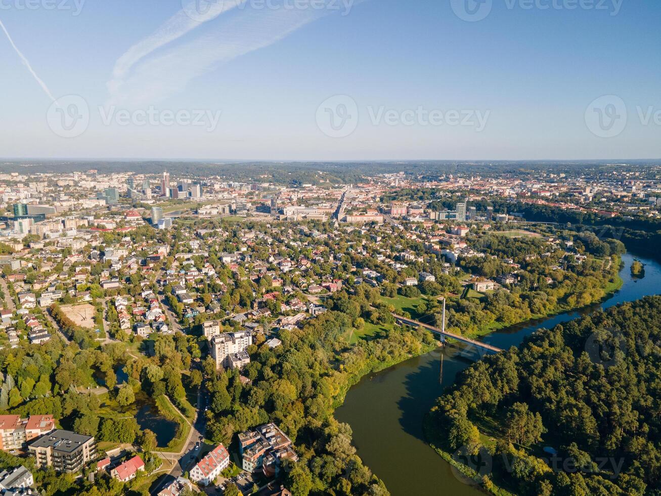Aerial panoramic view of a city with a river and green landscapes. Urban skyline with residential and commercial buildings surrounded by nature photo