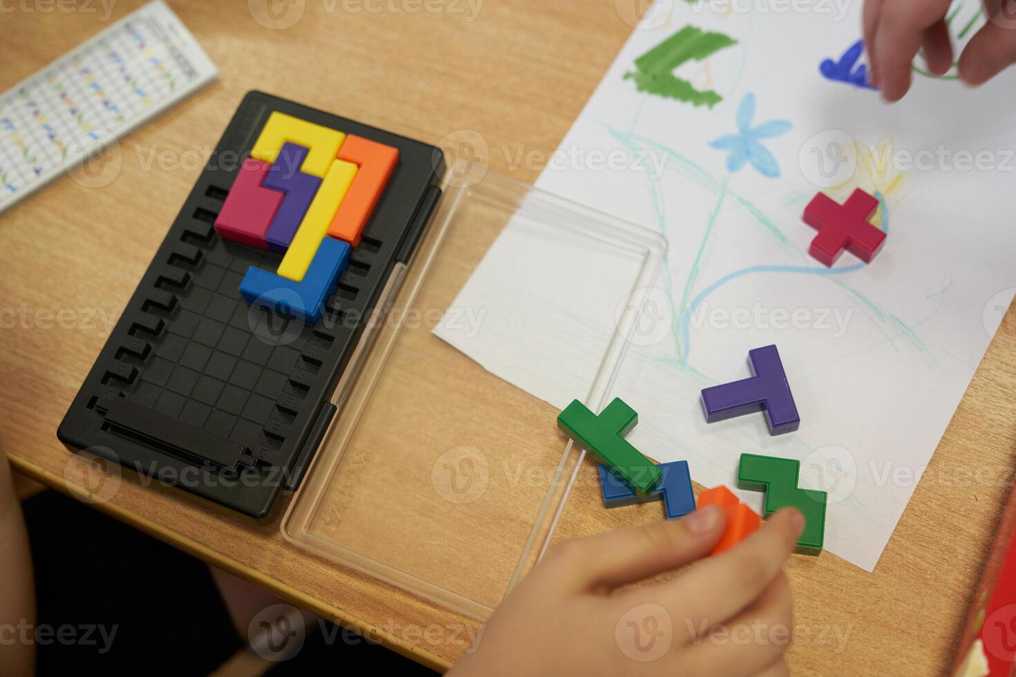 A plastic tetris game. Leisure time for children on vacation. An unrecognizable child is playing a plastic-based puzzle game. With space to copy photo