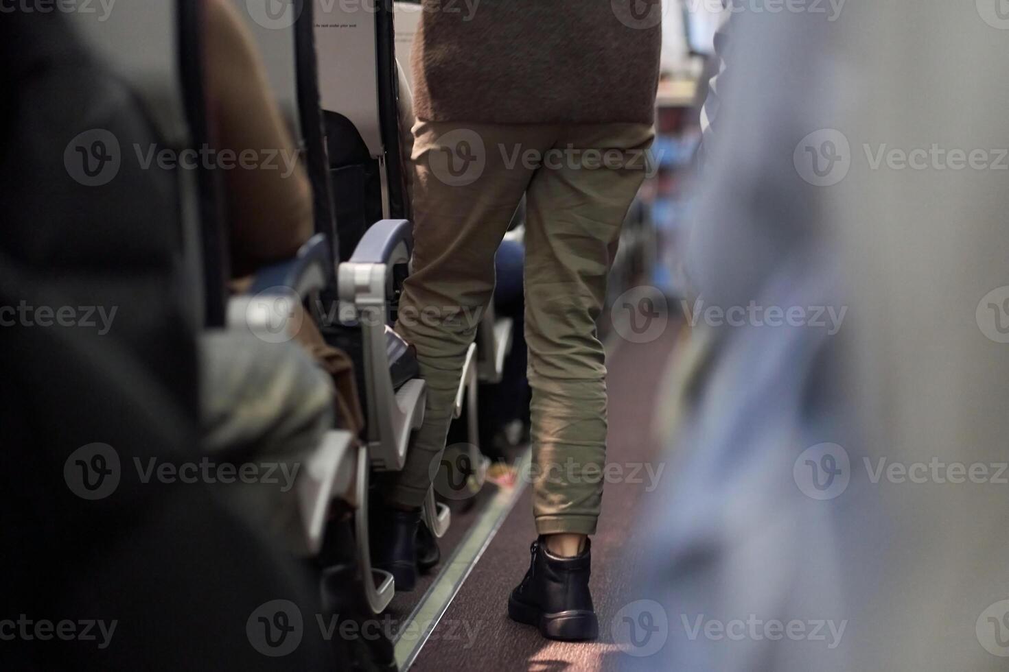 The man puts things on the shelf. Passengers sit along the row in the plane in their seats. The concept of travel. photo