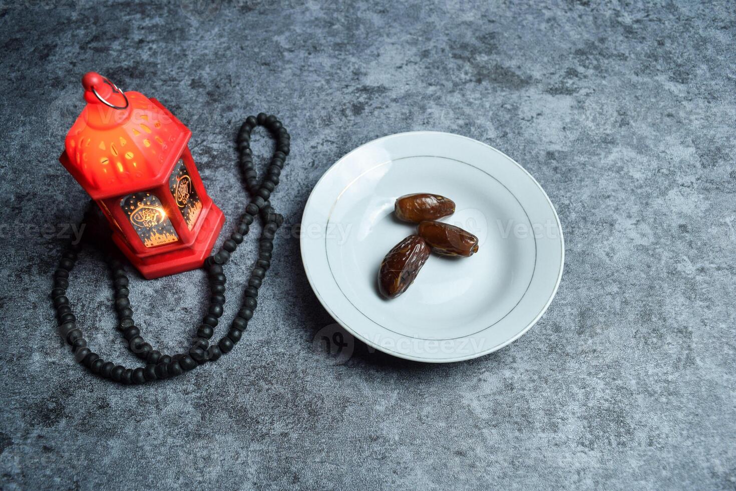 Dates, prayer beads, golden ramadhan lamp with islamic rosary beads on dark background ramadhan. photo
