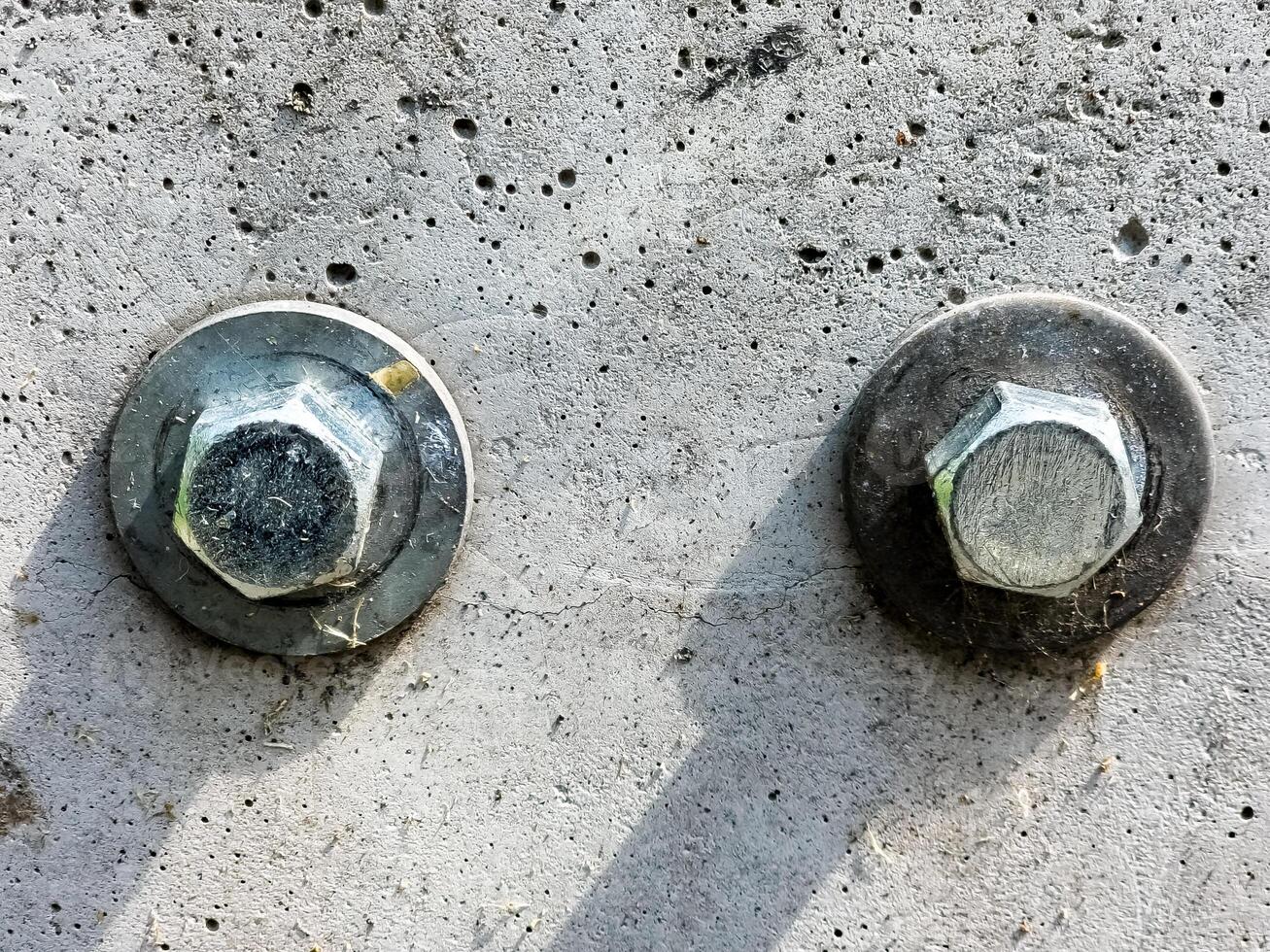 Close up of two bolts and washers fastened to a concrete surface. photo