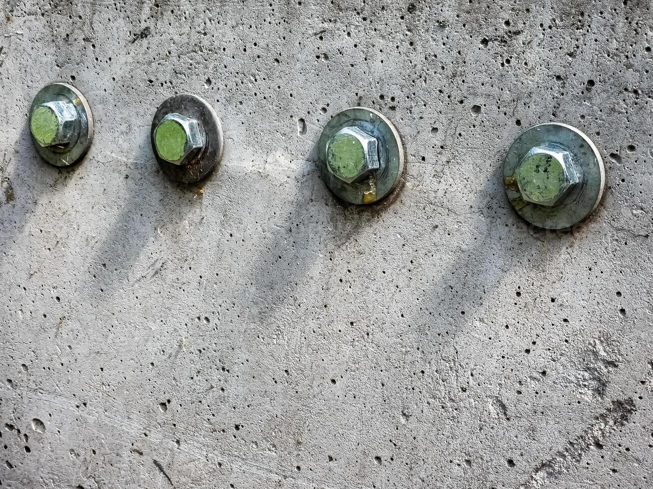 Close up of four bolts and washers fastening on a concrete surface. photo