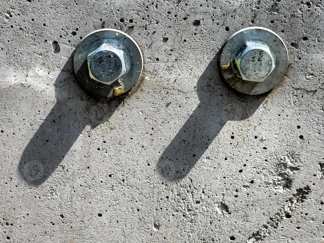 Close up of two bolts and washers fastened to concrete surface. photo