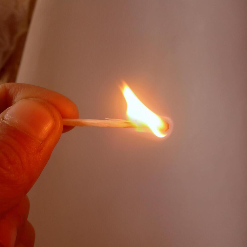 Burning Matchstick in Hand with Glowing Flame photo