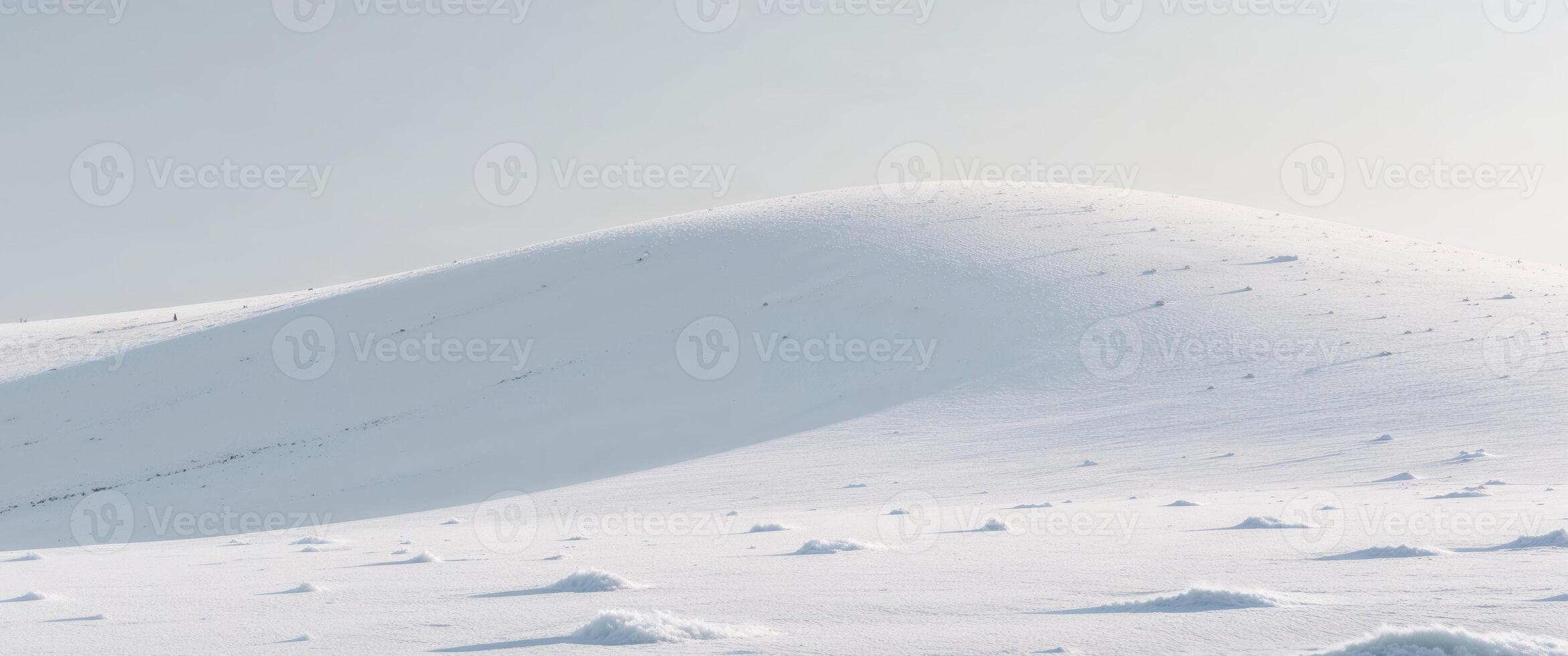 A white snow covered hill with a few small snow patches photo