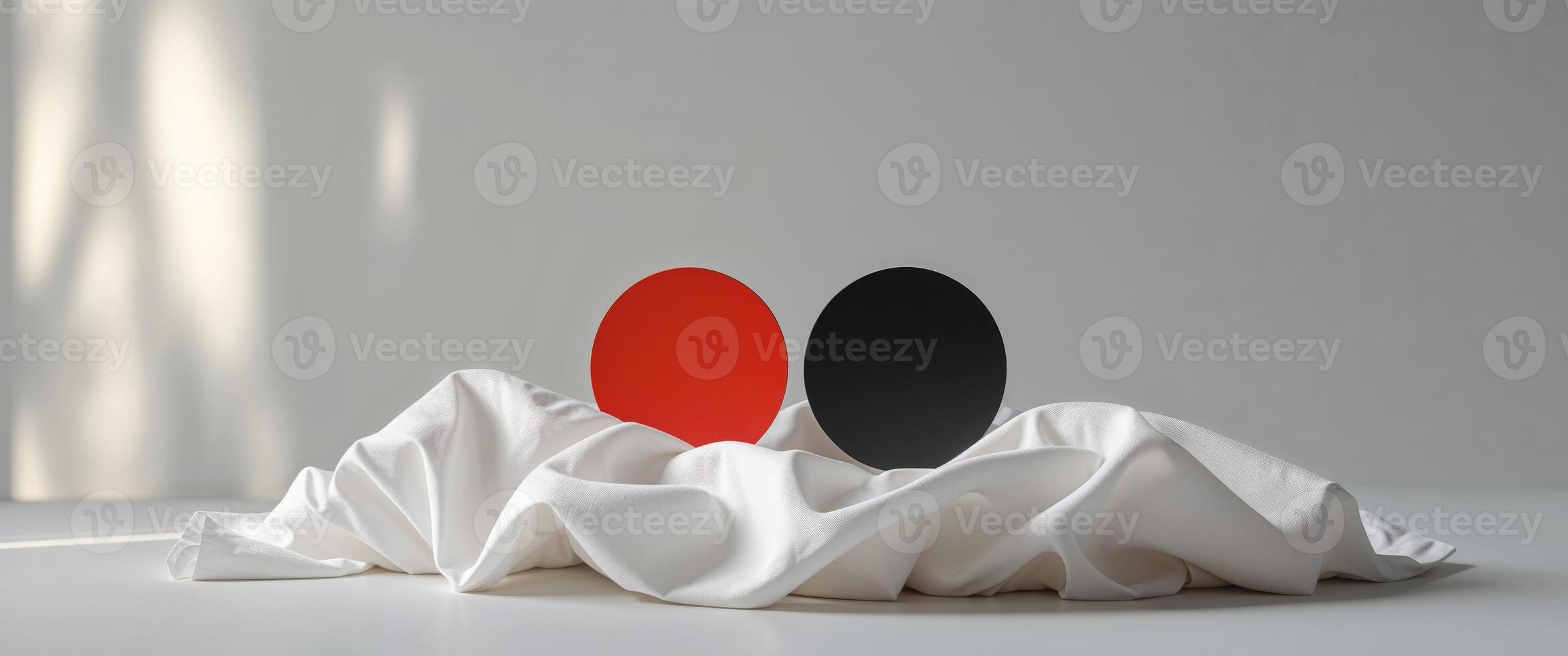 Two red and black balls sit on top of a white cloth photo