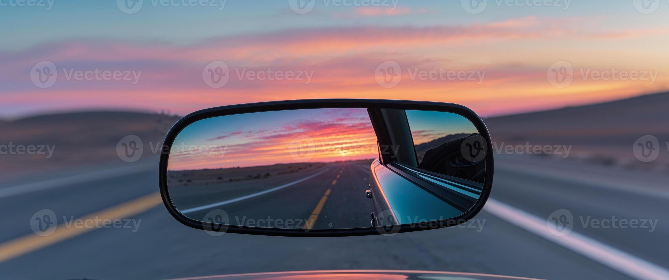 A rear view mirror on a car with a sunset in the background photo