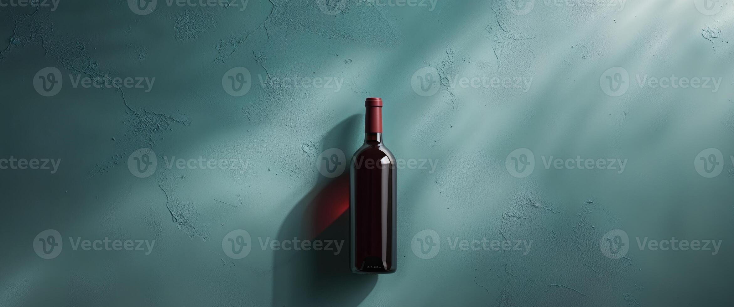 Red wine bottle on textured teal surface photo