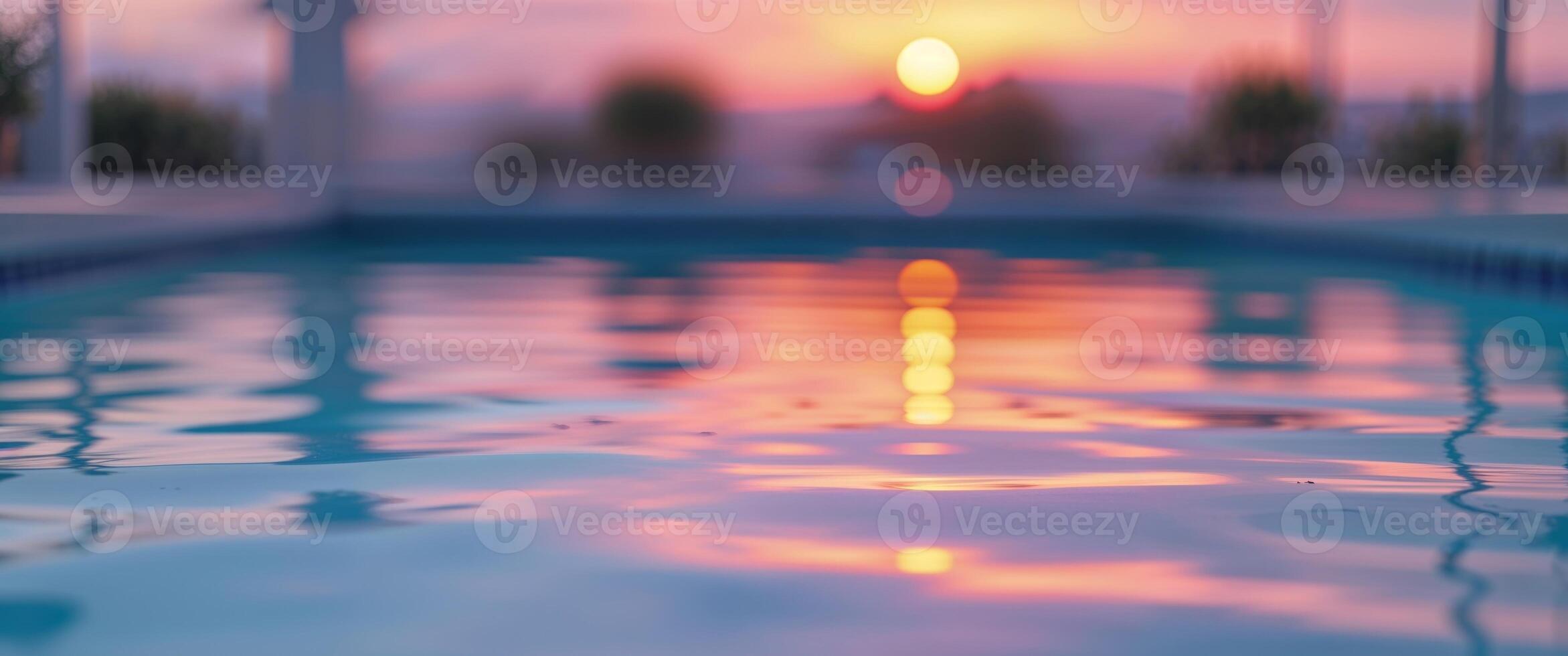 A pool with the sun setting in the background photo