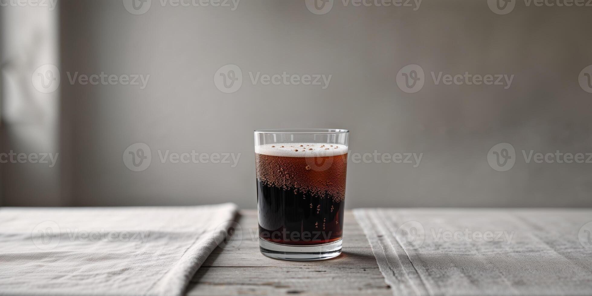 Glass of dark beverage with bubbles on a simple table setting in a studio photo