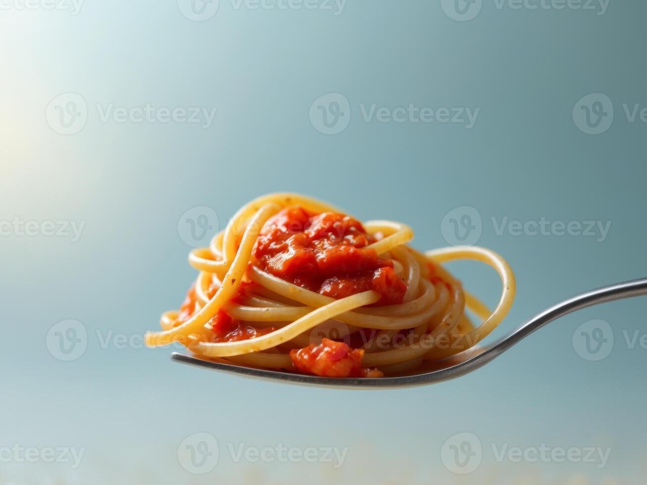 Spaghetti Twirled on Fork with Tomato Sauce on a Light Blue Background. photo