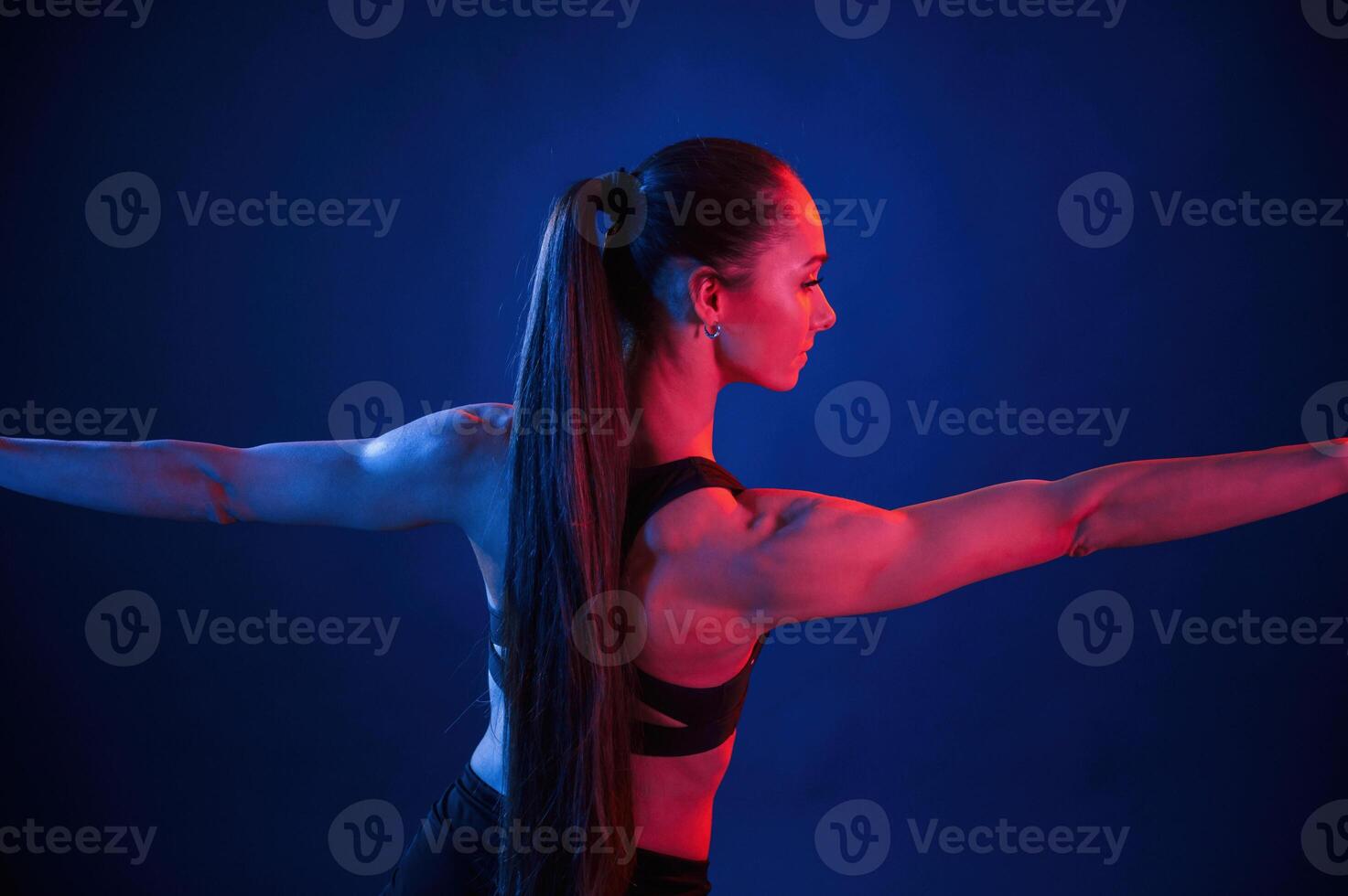 Flexible, body. Beautiful muscular woman is indoors in, the studio with neon lighting photo