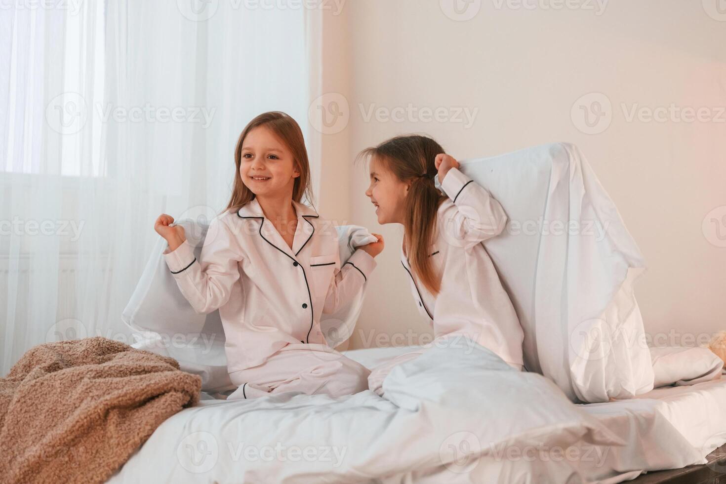 Playing pillow,, fight. Two little girls are having fun together in domestic room photo