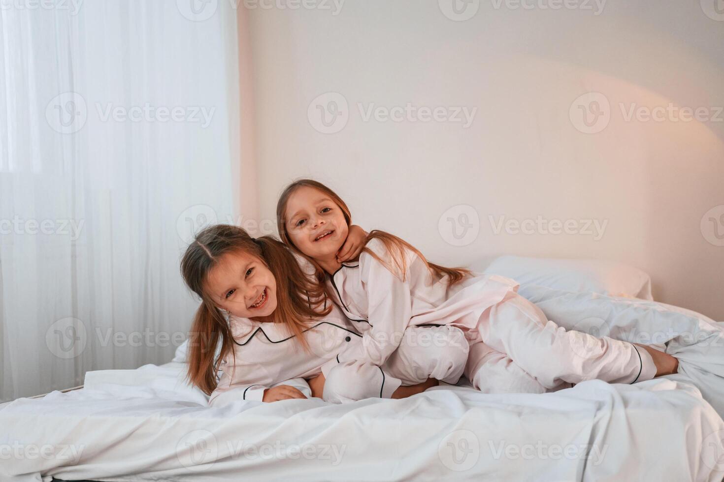 Cheerful and ,positive two little girls are playing and having fun together in bedroom photo