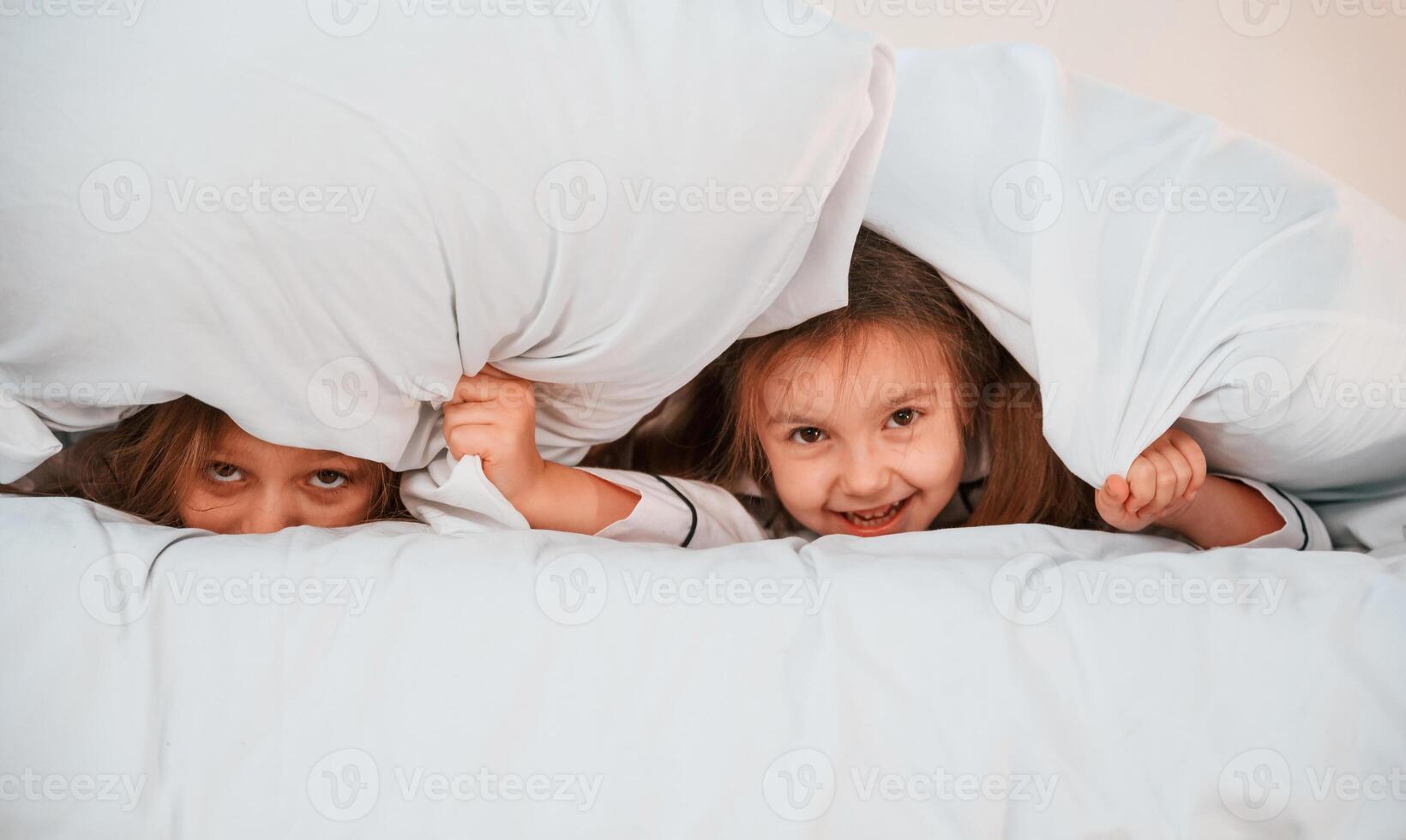 Kids are lying ,down on the bed. Two little girls are playing and having fun together in domestic room photo