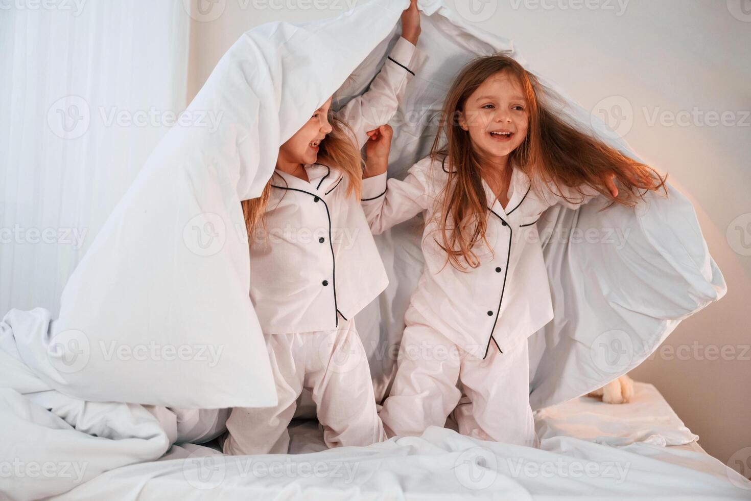 Holding ,the blanket. Two little girls are playing and having fun together in domestic room photo