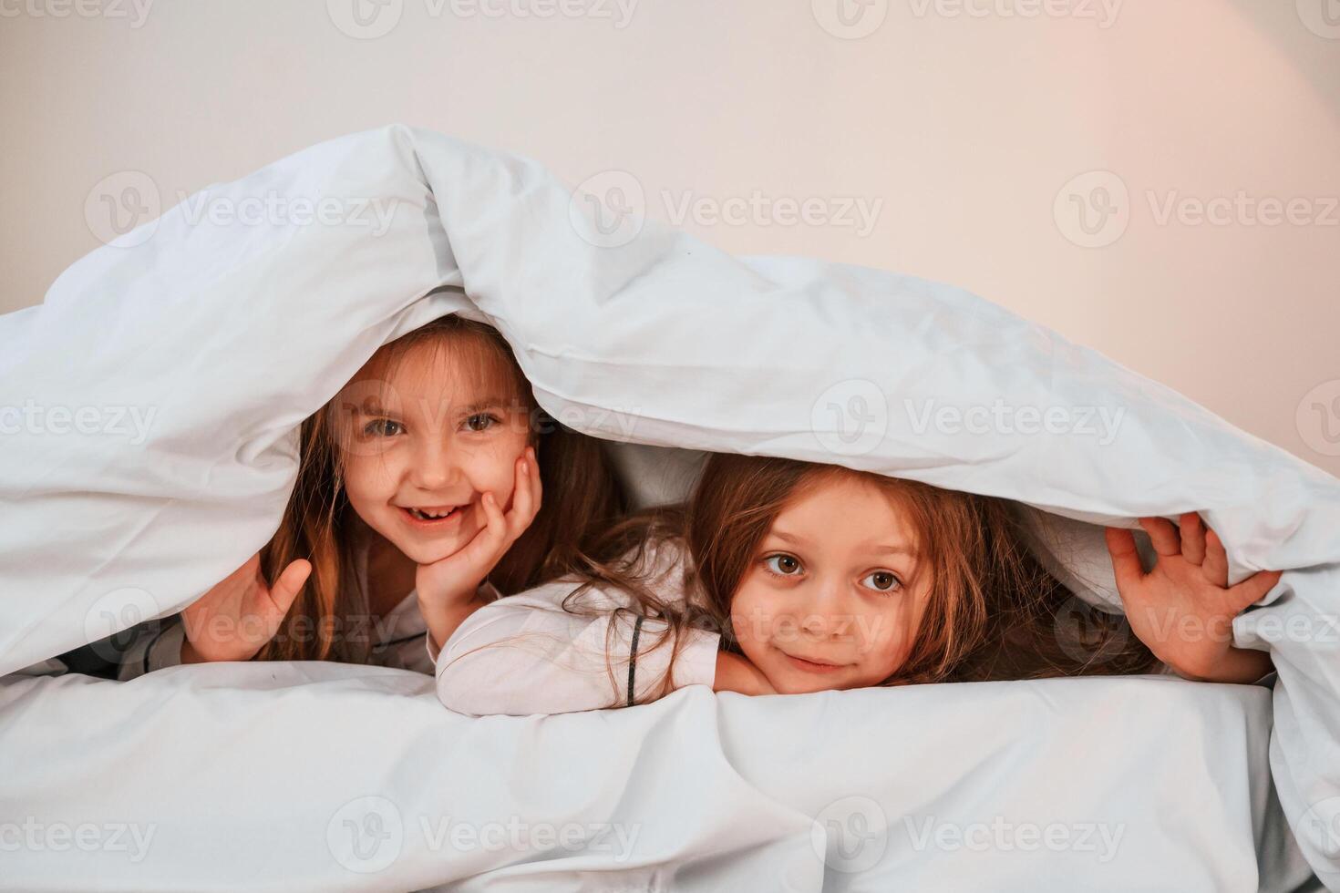 Cheerful,, and positive two little girls are playing and having fun together in bedroom photo