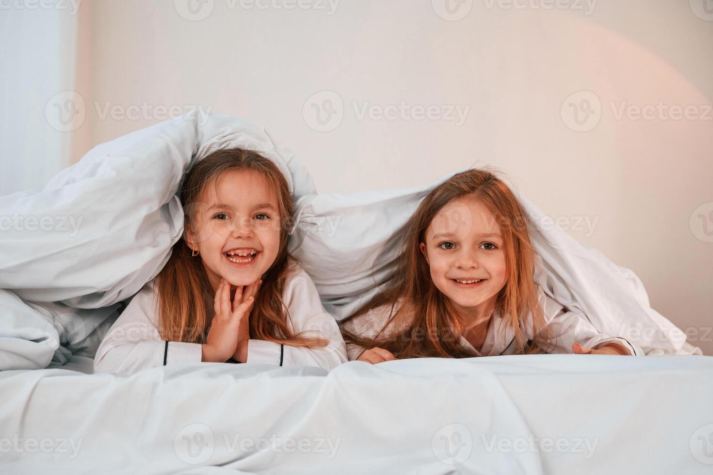 Kids ,are lying down on the bed. Two little girls are playing and having fun together in domestic room photo