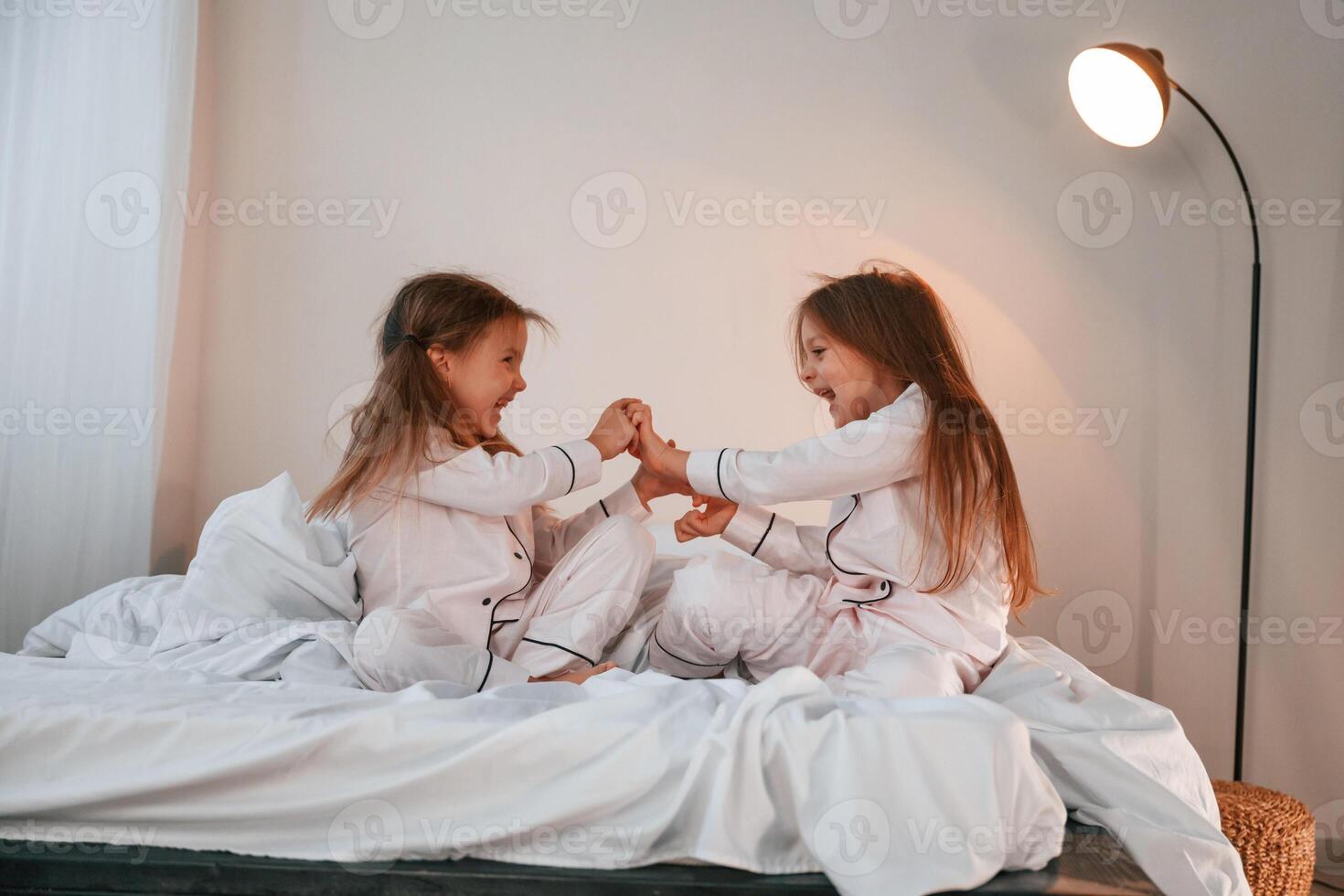 Side view. Playing, having fun. Two little girls are together in domestic room photo