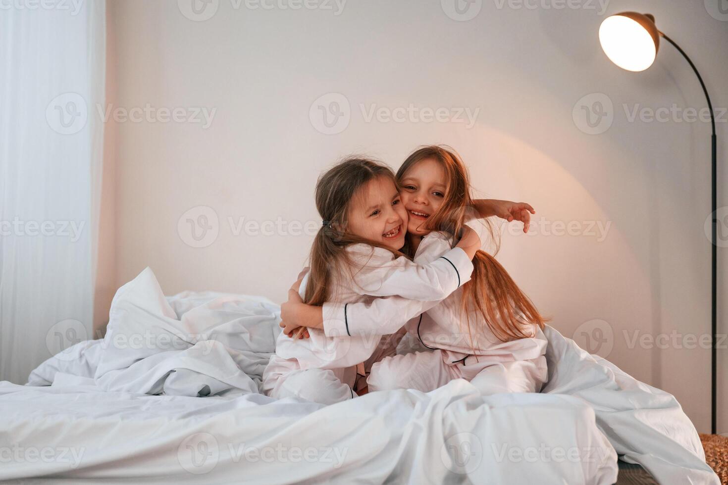 Embracing ,each other ,on the bed. Two little girls are playing and having fun together in domestic room photo
