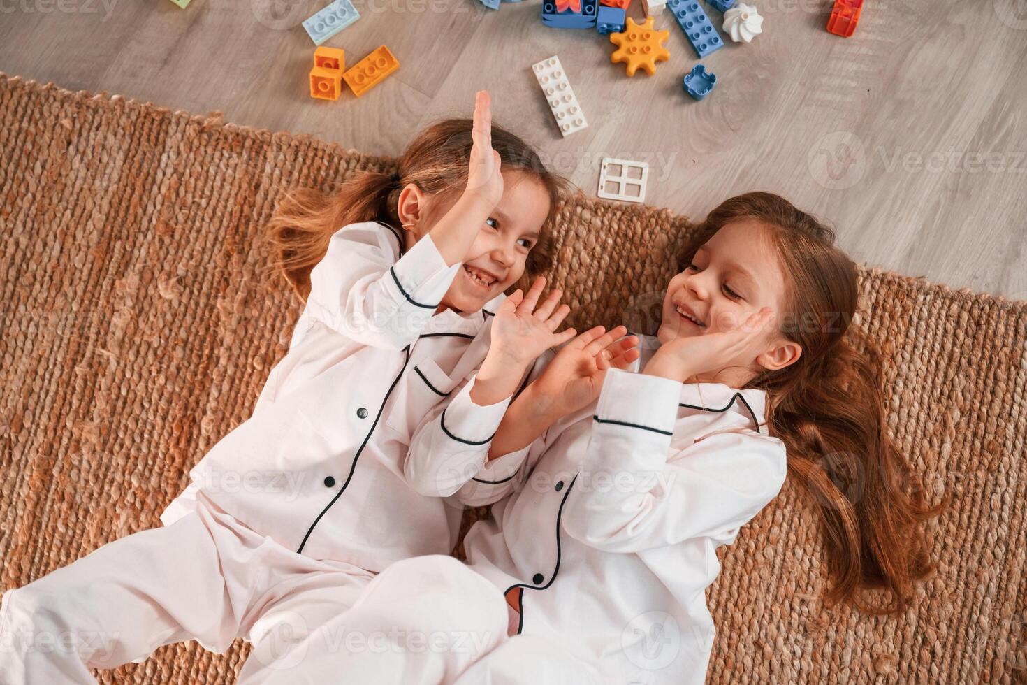 Top, view. Lying down. Construction plastic toys. Two little girls are playing and having fun together in domestic room photo
