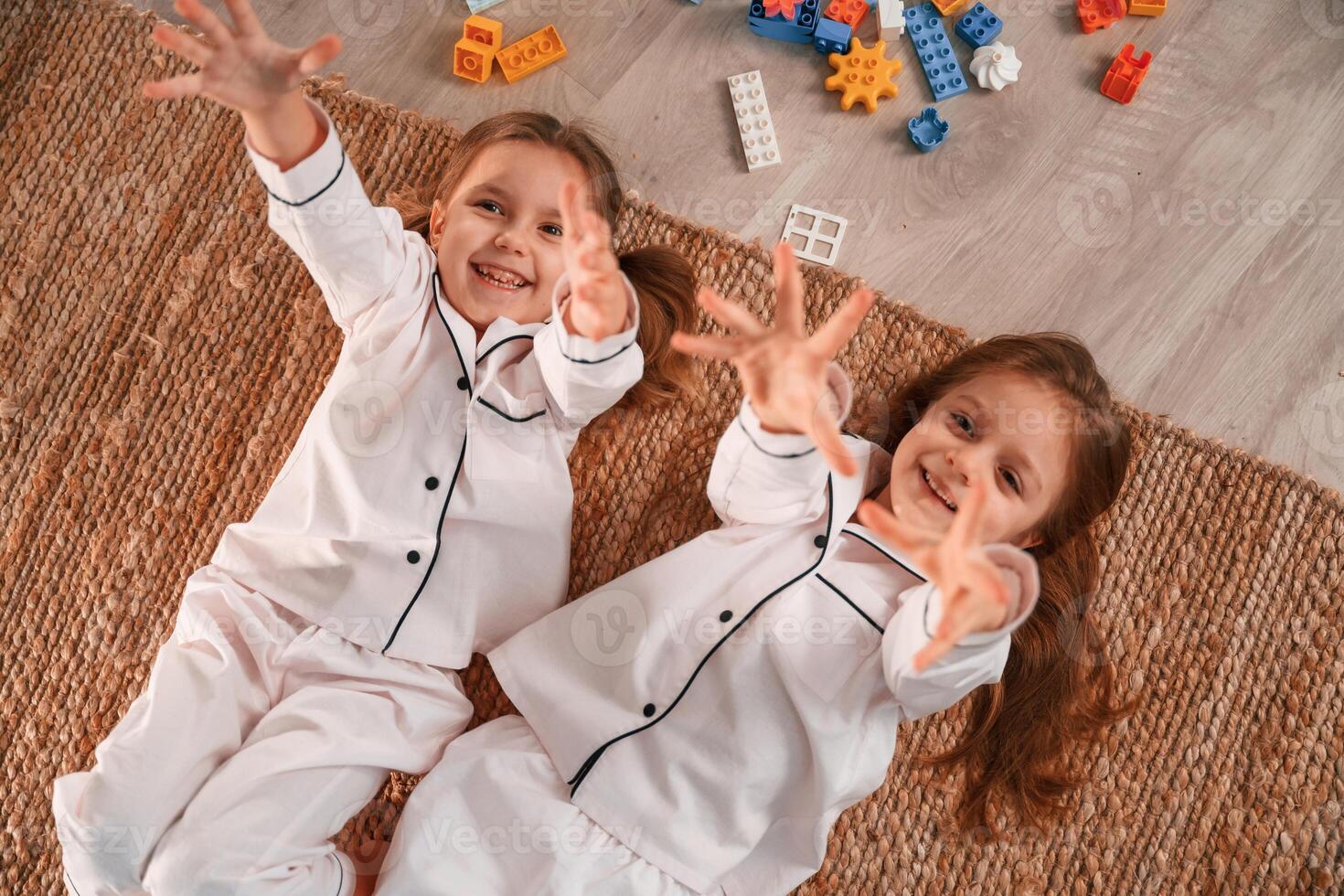 Top view.. Lying down. Construction, plastic toys. Two little girls are playing and having fun together in domestic room photo