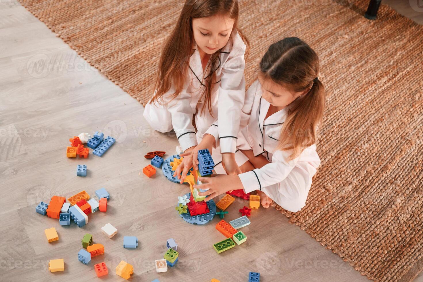 View, from the top. Playing construction game.. Two little girls are having fun together in domestic room photo