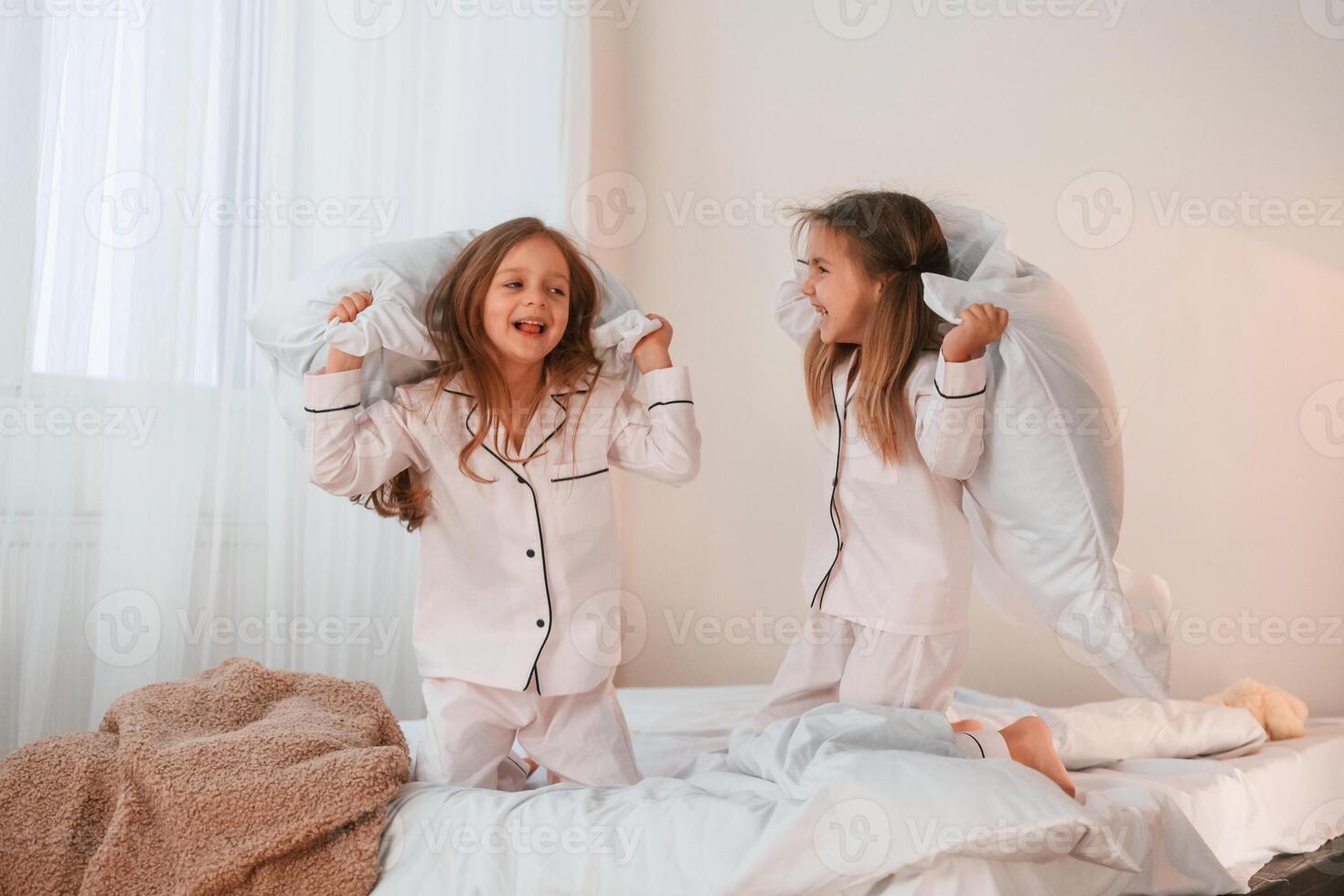 Playing ,pillow fight. Two little girls are having, fun together in domestic room photo