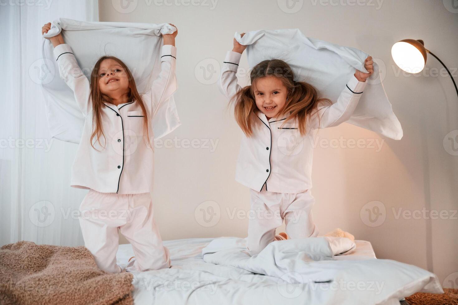 Active weekend. On the bed with pillows.. Two little ,girls are playing and having fun together in domestic room photo