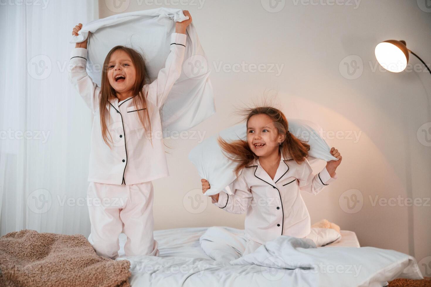 Active ,weekend. On the bed with pillows. Two little girls are playing and having fun together in domestic room photo