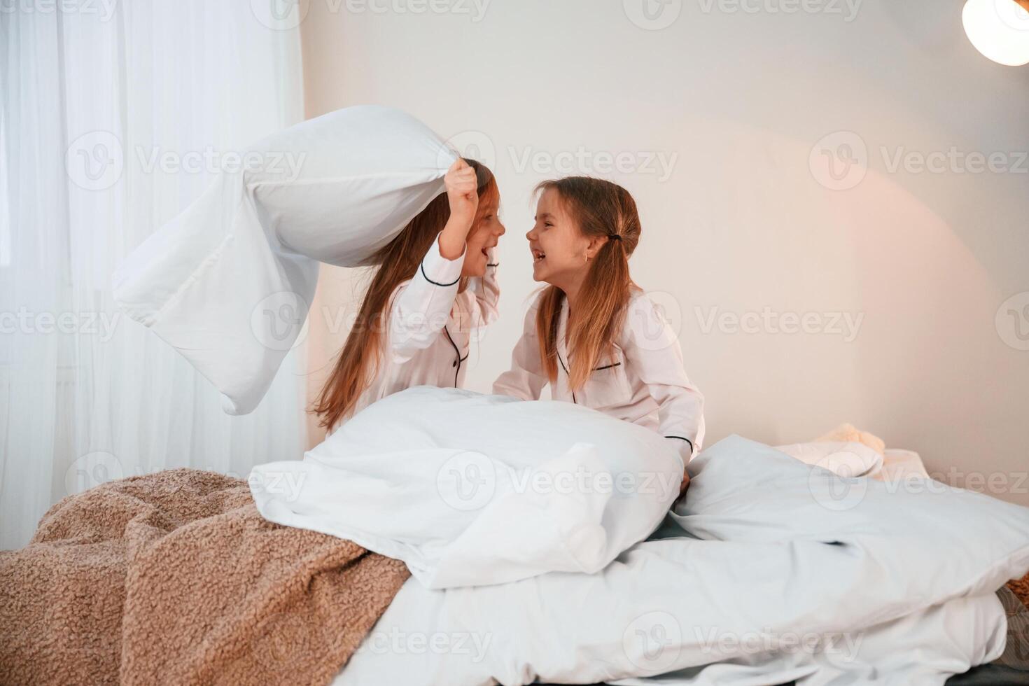Holding pillows ,and playing. Two little girls are ,having fun together in domestic room photo